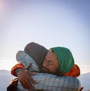 A photo of two people exchanging a hug at a summit.